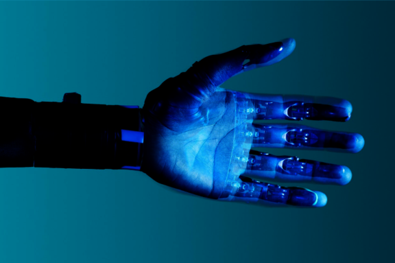 In blauem Licht gehaltene Doppelbelichtung eines menschlichen Arms mit einem Roboterarm  