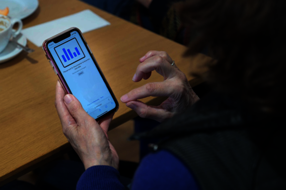 Foto von einem Mobiltelefon, das in der Hand einer Person bedient wird.  